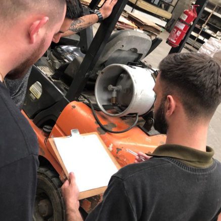 Técnico da Mais Proteção inspecionando um compressor com prancheta em uma indústria