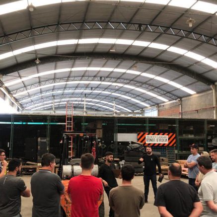 Treinamento com equipe reunida em galpão industrial